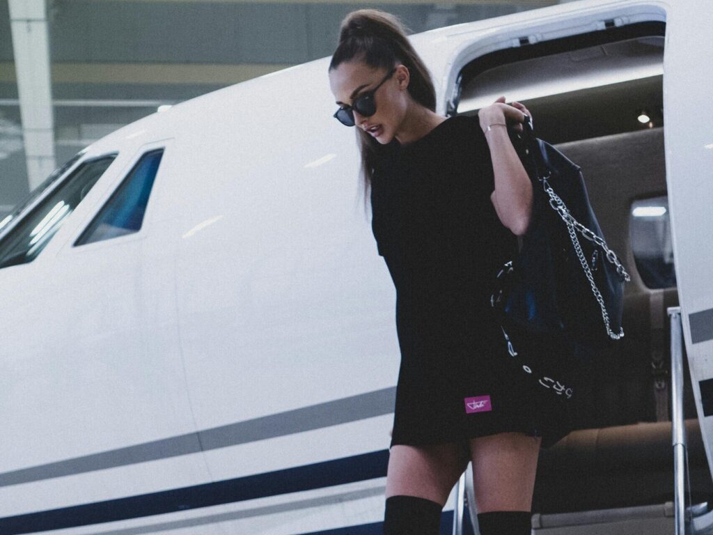 A fashionable woman in boots descends from a luxury private jet, exuding sophistication and wealth.